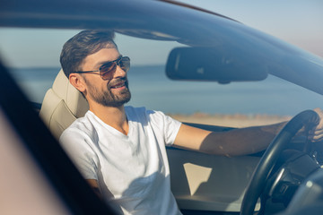 smiling guy driving cabriolet on the road