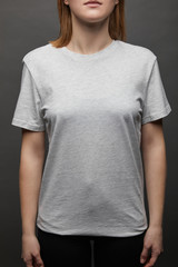cropped view of woman in blank basic grey t-shirt on black background