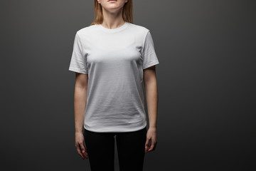 cropped view of woman in blank basic white t-shirt on black background