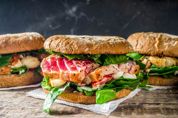 Various seafood and fish burgers assortment. Homemade healthy burger with grilled prawn, salmon, tuna, sea bass, fresh herbs, mozzarella cheese and baby spinach.