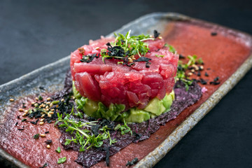 Gourmet fish tartar raw from tuna fillet with hashed avocado, wasabi and Japanese spice as closeup...