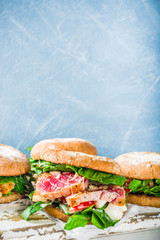 Various seafood and fish burgers assortment. Homemade healthy burger with grilled prawn, salmon, tuna, sea bass, fresh herbs, mozzarella cheese and baby spinach.