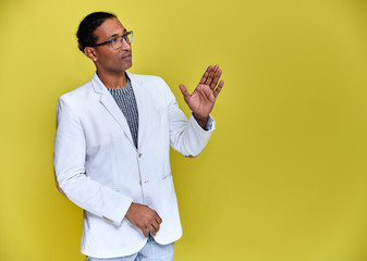 Portrait of a young African American man with short haircuts and a white-toothed smile in a white jacket on a yellow background. Standing and talking right in front of the camera.