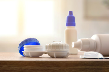 Closeup of contact lens products on wooden table in room