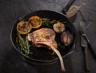 grilled pork steak tomahawk in a pan on a dark background