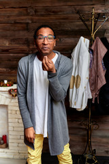 Vertical Portrait Young man with short-haired African-American glasses in ordinary clothes on a vintage wooden background in a home interior in a loft style. Standing right in front of the camera