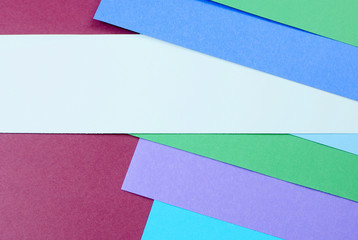 Layers of colored, rough textured construction paper creating a graphic template. Abstract design geometric style color blocks. Copyspace. Purple, blue, and green.