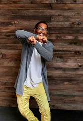 Vertical Portrait Young man with short-haired African-American glasses in ordinary clothes on a vintage wooden background in a home interior in a loft style. Standing right in front of the camera