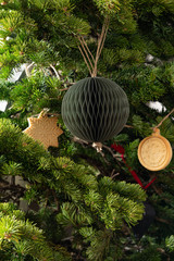 Handmade new year honeycomb ball from green paper and garland from stamped ginger cookies on fresh fir branches. New Year greeting card