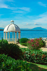 Beautiful white gazebo and tropical flower garden on Caribbean ocean background, summer mountain view , Sosua, Puerto Plata, Dominican Republic