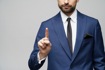 Businessman point finger at invisible screen, hand pushing touch screen, business man pressing digital virtual button isolated over grey background - Powered by Adobe