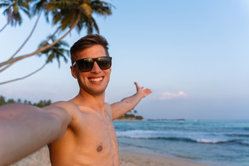 young happy man taking a self portrait picture in his holiday in a tropical location