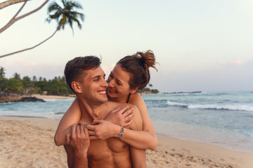 Fototapeta premium young happy couple piggyback in a tropical beach during sunset