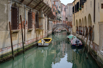 Fototapeta na wymiar Narrow canal between residential buildings, old walls, boats on the water. Venice, Italy.