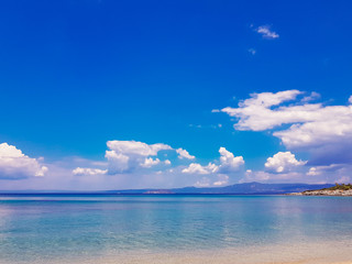Fototapeta na wymiar Seascape against the sky with white clouds and mountains. Aegean Sea, Greece.