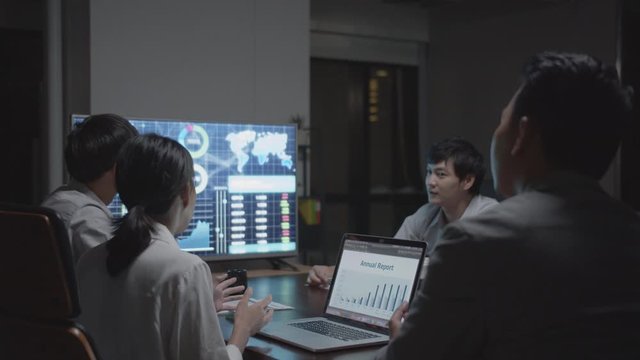 Asian business team meeting, discussion, brainstorming and talking with marketing monthly report on laptop and Monitor in conference meeting room at office overtime. Working late concept