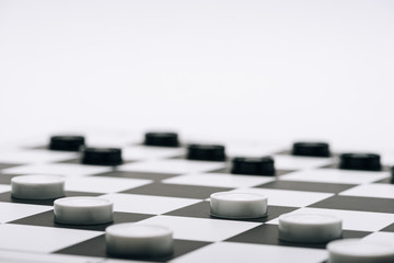 Selective focus of checkers on chessboard isolated on white - obrazy, fototapety, plakaty