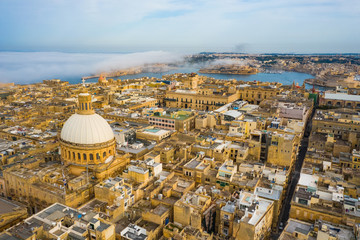 Aerial view of Valletta, dome, church. Clouds, fog on blue sky. Malta country 