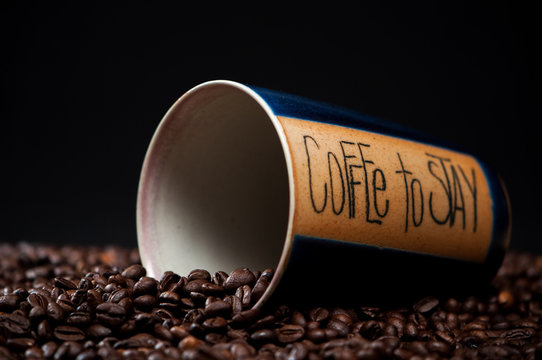 Liegender Kaffeebecher mit Kaffeebohnen