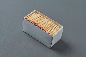 Full big cardboard matchbox of many matchsticks with red sulfur on dark concrete table on kitchen. Close-up