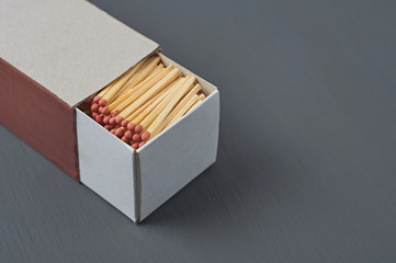 Full big cardboard matchbox of many matchsticks with red sulfur on dark concrete table on kitchen. Space for text