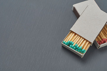 Two cardboard matchboxes of many matchsticks with red and green sulfurs on dark concrete table on kitchen. Space for text