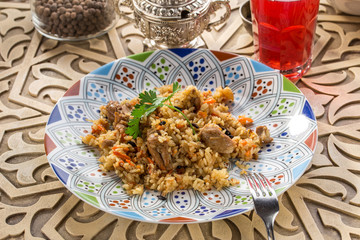 pilaf rice with lamb and glass of red drink on oriental wooden table