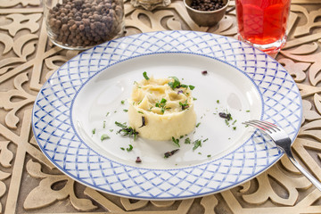 Mashed potato with dill and glass of red drink on orienral wooden table