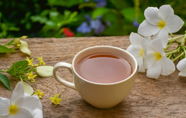 White cup of hot tea and flowers on wooden board .Afternoon teatime in the garden. Selective focus.