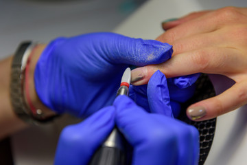 Hardware milling cutter for removing gel polish. Apparatus manicure in salon. Female manicurist with electric nail drill remove old gel from client nails. Process of replacing old shellac.