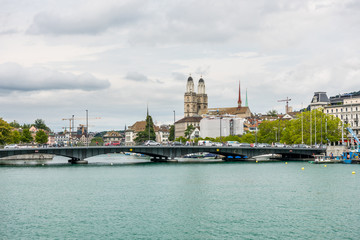 Fototapeta premium View of the historic buildings and bridge of Zurich at the bank of Limmat River and Zurich lake, with landmark of Zurich University, and Grossmunster (Great Church)