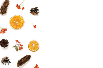 Border made of dried oranges, pine cones and red rowan berries on white. Flat lay composition