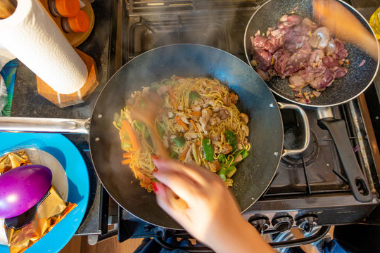 Cooking filipino noodles and chicken livers on a hob in a home kitchen.