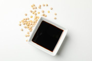 Bowl of soy sauce, soy beans on white background, space for text. Top view