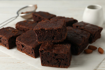 Chocolate cake slices, almond and strainer on white background, close up