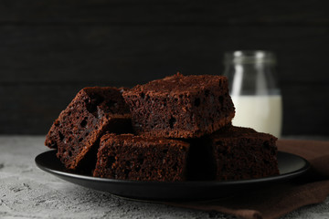 Plate with chocolate cake slices and bottle of milk on grey table, close up