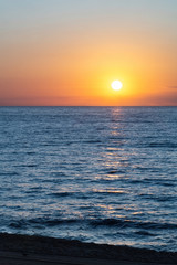 Obraz premium Sun is rising above the calm blue sea.