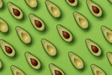 Summer food pattern. Avocado halves on green background. Top view. Flat lay