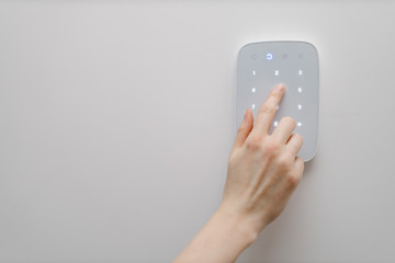 Home security concept. Woman hand entering a home security code