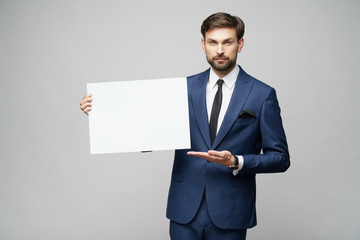 Young businessman holding blank signs over grey background