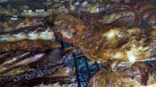 Close up shot of crispy and roasted pieces of chicken and beef in Argentinian asado