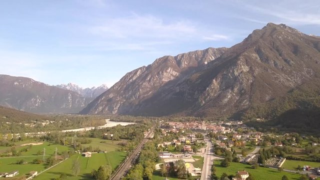 Aerial view of a small historic town Venzone in Northern Italy with red tiled roofs of old buildings and majestic Alps mountains.