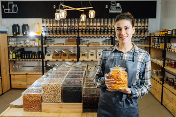 woman is bying products in zero waste shop with glass jars, cotton bags with out plastic packages