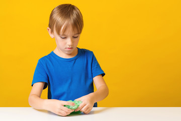 Happy boy makes a slime at table. Homemade popular toy slime. Child plays with slime