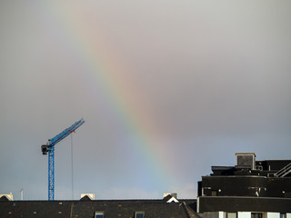 Blue crane  over building roofs, Rainbow in the sky.