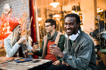 Smiling Afro American guy looking at camera while sitting in cafe