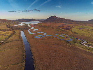 Aerial view on a small rivers in Connemara National park, Mountains and empty fields, Blue cloudy sky, County Galway, Ireland.