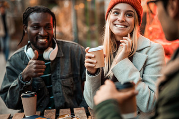 Two friends sitting in cafe and holding coffee