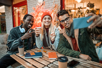 Three friends making selfie in a street cafe