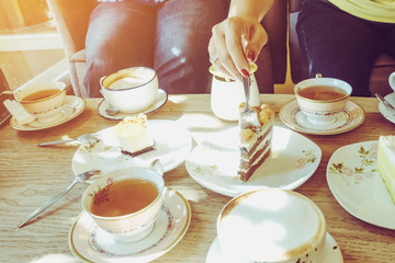 Happiness female friends meeting and drinking tea or coffee with cakes together at cafe in the afternoon. People, leisure and communication concept. Selective focus.
